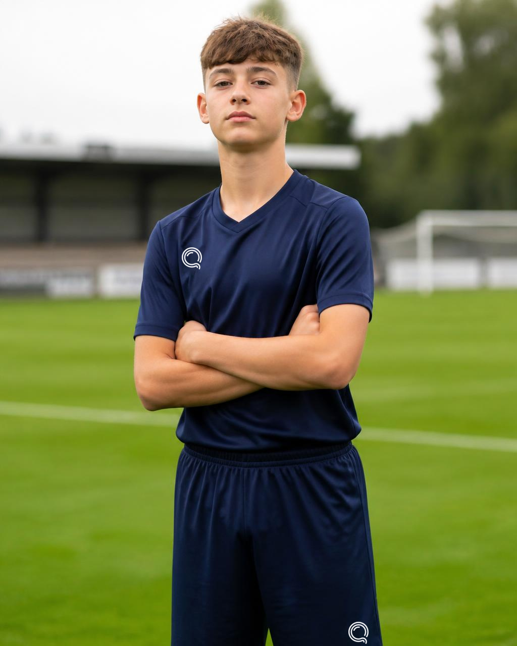 Young athlete in sports kit standing confidently on a football pitch